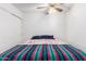 Simple bedroom featuring a ceiling fan, a bed with decorative blanket, and a window at 4401 W Lewis Ave, Phoenix, AZ 85035