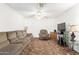 Bright living room featuring a sofa, chair, and a ceiling fan with white walls at 4401 W Lewis Ave, Phoenix, AZ 85035