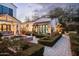 Wide view of an amazing landscaped backyard with a covered patio, grill, fountain, and white home at 4716 N Dromedary Rd, Phoenix, AZ 85018