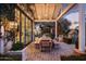 Illuminated outdoor dining area with wooden table and bench seating at twilight, with an ivy covered home at 4716 N Dromedary Rd, Phoenix, AZ 85018