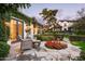 Stone patio with outdoor seating, red flowers, and ivy-covered house with glass doors at 4716 N Dromedary Rd, Phoenix, AZ 85018