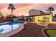 Backyard pool with a covered patio area, green lawn, and palm trees with colorful sunset at 5761 E Tierra Buena Ln, Scottsdale, AZ 85254