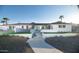 Charming white single-story home featuring a well-manicured landscape, complemented by palm trees and a blue door at 5801 N 22Nd Pl, Phoenix, AZ 85016