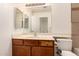 Bathroom with wood cabinets, neutral countertop, mirror, and toilet at 5808 E Brown Rd # 110, Mesa, AZ 85205