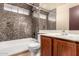 Well-lit bathroom featuring a sleek vanity, toilet, tub, shower, and stone tile accent wall at 5808 E Brown Rd # 110, Mesa, AZ 85205