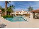 Community pool with lounge chairs surrounded by lush greenery and a clear blue sky at 5808 E Brown Rd # 110, Mesa, AZ 85205