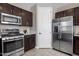 Kitchen showcasing stainless steel appliances, modern dark wood cabinets, and tile flooring at 7057 E Diamond St, Scottsdale, AZ 85257