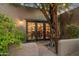 Exterior patio at dusk featuring lush landscaping, mature trees, and classic sconce lighting at 8008 N 66Th St, Paradise Valley, AZ 85253