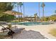 Backyard pool with a stone surround, mature landscaping, a pergola with seating, and tall palm trees at 8008 N 66Th St, Paradise Valley, AZ 85253