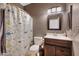 Well-lit bathroom with dark wood vanity, decorative mirror and charming fish-themed shower curtain at 910 W Aspen Way, Gilbert, AZ 85233