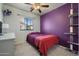 Cozy bedroom with bright purple accent wall, plush carpet and a window with natural light at 910 W Aspen Way, Gilbert, AZ 85233