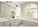 Light-filled bathroom featuring dual sinks, a tub, and a large window at 9224 E Windrose Dr, Scottsdale, AZ 85260