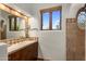 Bathroom with vanity, a large mirror, and a window with views of the lush landscaping at 10040 E Happy Valley Rd # 289, Scottsdale, AZ 85255