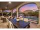 Inviting outdoor dining area under an arched patio, offering views of the pool and sunset sky at 10040 E Happy Valley Rd # 289, Scottsdale, AZ 85255