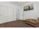 Bedroom features a cozy brown chair, sliding closet doors and neutral paint scheme at 10212 W Wier Ave, Tolleson, AZ 85353