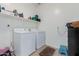 Functional laundry room includes washer, dryer, tile floor and storage shelves at 10212 W Wier Ave, Tolleson, AZ 85353