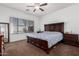 This primary bedroom features a ceiling fan, large window, and dark wood furniture at 10212 W Wier Ave, Tolleson, AZ 85353