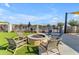 Outdoor fire pit with chairs, green space and swimming pool under a blue partly cloudy sky at 10455 E Thornton Ave, Mesa, AZ 85212