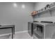 Functional laundry room with modern washer and dryer, a sleek black folding table, and built-in storage shelves at 10455 E Thornton Ave, Mesa, AZ 85212