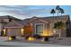 Charming single-story home featuring desert landscaping, a neutral color palette, and well-lit exterior at dusk at 1314 W Windsong Dr, Phoenix, AZ 85045