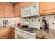 Well-lit kitchen featuring oak cabinets, granite countertops, and a GE microwave above a white electric stove at 1403 E Las Colinas Dr, Chandler, AZ 85249