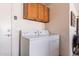 Bright laundry room featuring white washer and dryer with overhead cabinets for storage at 1403 E Las Colinas Dr, Chandler, AZ 85249