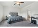 Comfortable bedroom with a ceiling fan, gray furnishings, carpet, and view to the bathroom at 14317 W Faye Way, Surprise, AZ 85387