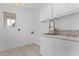 Bright laundry room with white cabinets, tile countertops, stainless steel faucet, and a window offering natural light at 14401 N 29Th St, Phoenix, AZ 85032