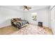 Cozy bedroom with wood-look tile flooring, ceiling fan, and bright window view at 15602 N Nicklaus Ln, Sun City, AZ 85351