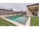 Beautiful pool with a baja shelf, framed by artificial turf and stone accent wall at 18625 W Williams Rd, Surprise, AZ 85387