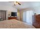 Bedroom with ceiling fan, TV atop dresser, sliding door access to the backyard, and a view of the en-suite bathroom at 1899 W Prospector Way, San Tan Valley, AZ 85144