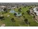 Aerial view of the golf course, featuring lush green fairways, a scenic pond, and mature trees at 19817 N Ponderosa Cir, Sun City, AZ 85373