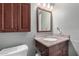 Charming bathroom featuring cherry-wood vanity with granite countertop, decorative mirror, and cabinet storage at 2129 N Apollo Ct, Chandler, AZ 85224