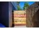 A colorful wooden plank gate with an iron latch is enclosed by two textured stucco walls at 2217 N 37Th Pl, Phoenix, AZ 85008