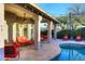 A covered patio with outdoor seating and ceiling fans overlooks a lush backyard with a sparkling pool at 24024 N 74Th St, Scottsdale, AZ 85255