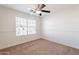 Bedroom featuring ceiling fan, neutral carpet and paint, and a large window at 3043 W Melinda Ln, Phoenix, AZ 85027