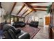 Spacious living room featuring exposed beams, natural light and comfortable black leather seating at 3160 E Fox St, Mesa, AZ 85213