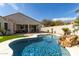 Sparkling pool with rock waterfall feature, set in a lush backyard with a covered patio area at 3781 S Pablo Pass Dr, Gilbert, AZ 85297