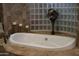 Close up of soaking tub with tile surround, glass block window, decorative flowers and candles at 39610 N 12Th St, Phoenix, AZ 85086