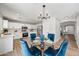 Bright dining area features a glass table with blue velvet chairs and a modern light fixture, adjacent to kitchen at 43819 W Wolf Dr, Maricopa, AZ 85138