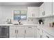 Well-lit kitchen features white cabinets with modern hardware, quartz countertops, stainless steel appliances, and stylish backsplash at 43819 W Wolf Dr, Maricopa, AZ 85138