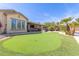 Beautiful backyard showcasing putting green, outdoor bar, palm trees, lush landscaping, and covered patio at 450 E Alamosa Dr, Chandler, AZ 85249