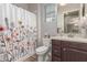 Functional bathroom featuring a floral shower curtain, vanity sink, toilet, and natural light from the window at 4684 N 206Th Ave, Buckeye, AZ 85396