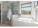 Bright bathroom featuring a soaking tub, glass shower with tile surround, and a window with natural light at 4684 N 206Th Ave, Buckeye, AZ 85396