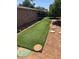 Backyard featuring an outdoor artificial grass lawn with stepping stones and an adjacent red brick home exterior at 5618 E Des Moines St, Mesa, AZ 85205