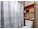 Bathroom features a toilet, wooden shelving, and a patterned shower curtain at 562 W Enchanted Desert Dr, Casa Grande, AZ 85122