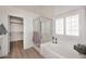 Bright bathroom showcasing a tub with jets, glass shower, and shuttered windows for natural light at 5624 E Garnet Ave, Mesa, AZ 85206