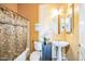 Quaint bathroom with pedestal sink, round mirror, decorative shower curtain, and warm, inviting colors at 5634 N 82 Ave, Glendale, AZ 85303