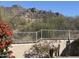 Backyard view with a white fence, and a hill in the background, complemented by flowers and desert foliage at 6432 E Old Paint Trl, Carefree, AZ 85377