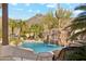 Gorgeous pool with rock waterfall, mature palms, and a partial view of the surrounding mountains at 6432 E Old Paint Trl, Carefree, AZ 85377